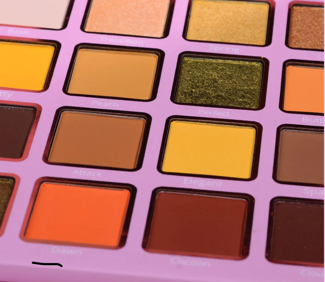 Makeup palette with various colored eyeshadows on a pink background