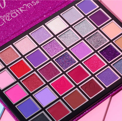 Makeup palette with various colors on a pink background