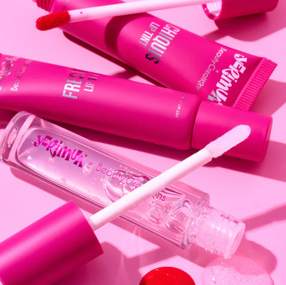 Pink lip gloss tubes with applicators on a pink background